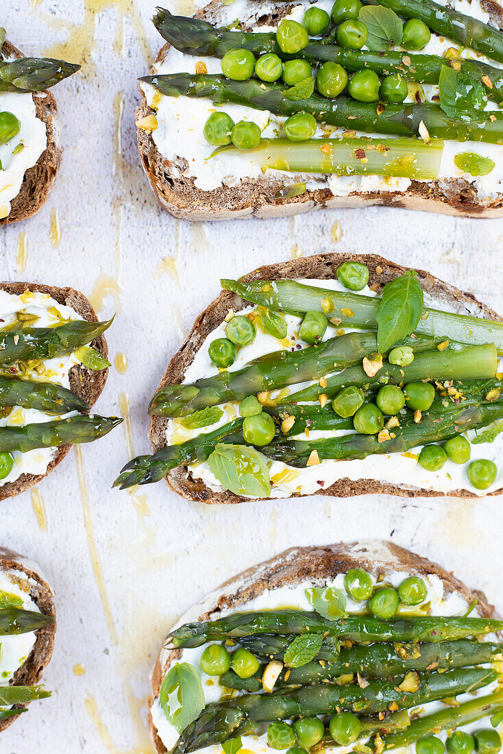 Bread slices with goat cheese, green peas and asparagus