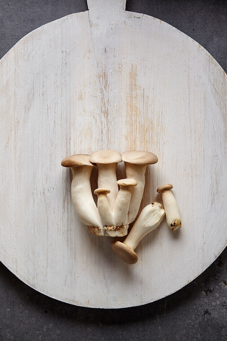 Trumpet mushrooms on a white wooden board