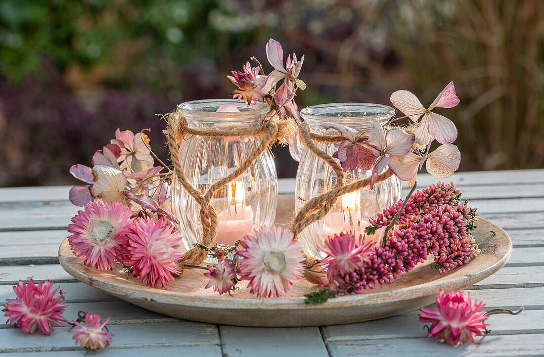 Autumn decoration, straw flowers from common heather (Calluna Vulgaris), hydrangeas (Hydrangea) and lanterns on plates