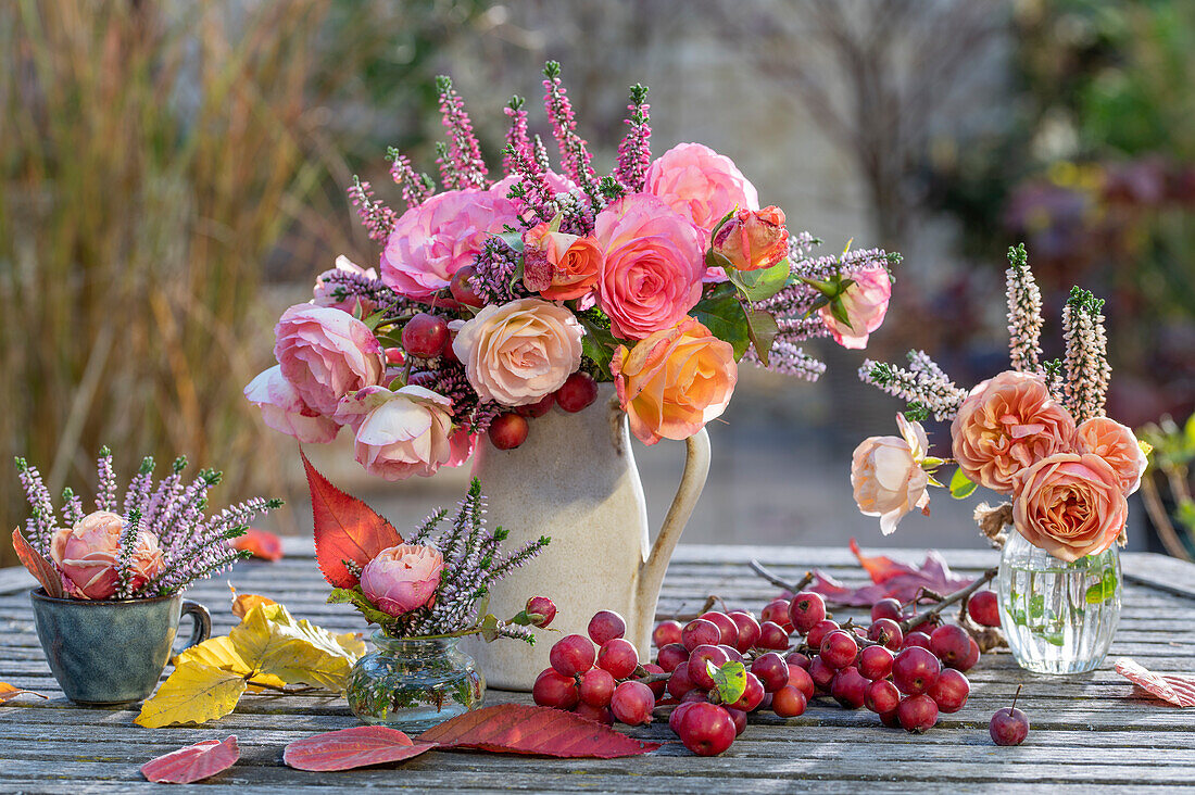 Herbstliche Tischdeko aus Rosenstrauß (Rosa), Besenheide (Calluna vulgaris) und Zierapfel