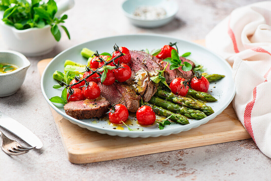 Fried steak with green asparagus and cherry tomatoes