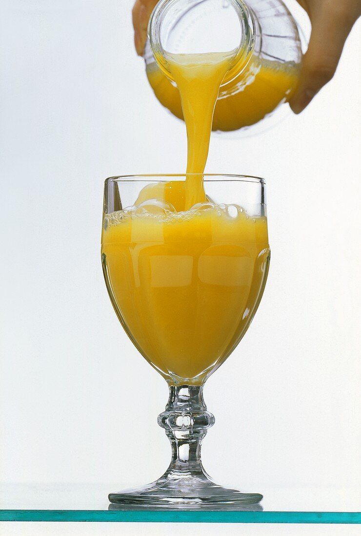 Orange Juice Pouring into a Glass From Bottle