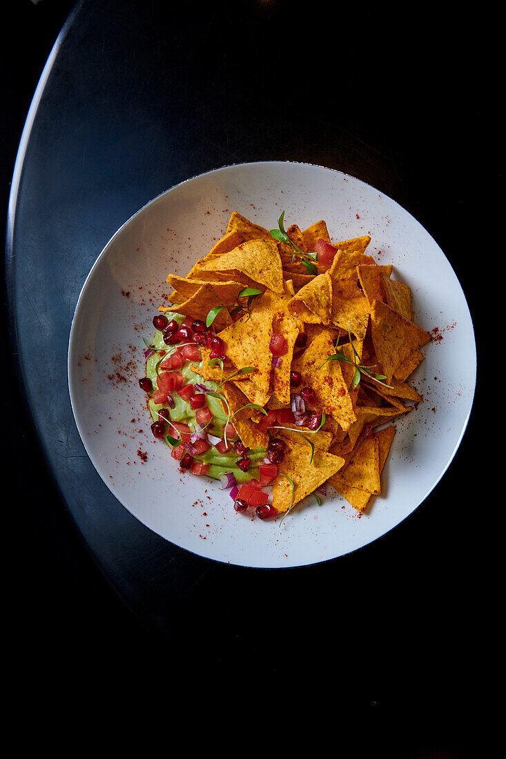 Nachos with guacamole and pomegranate seeds