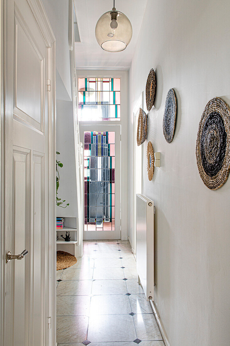 Narrow passageway with wall decoration, stained glass window in the background