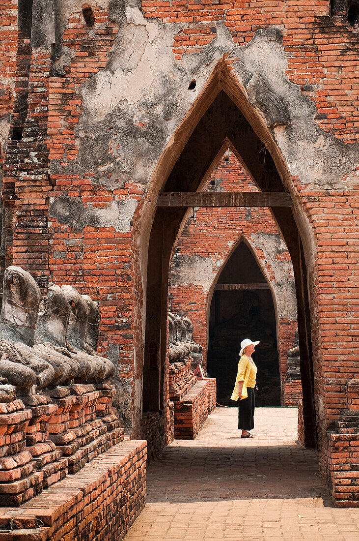 Besucherin in den Ruinen des buddhistischen Tempels Wat Chaiwatthanaram in Ayutthaya, Thailand.