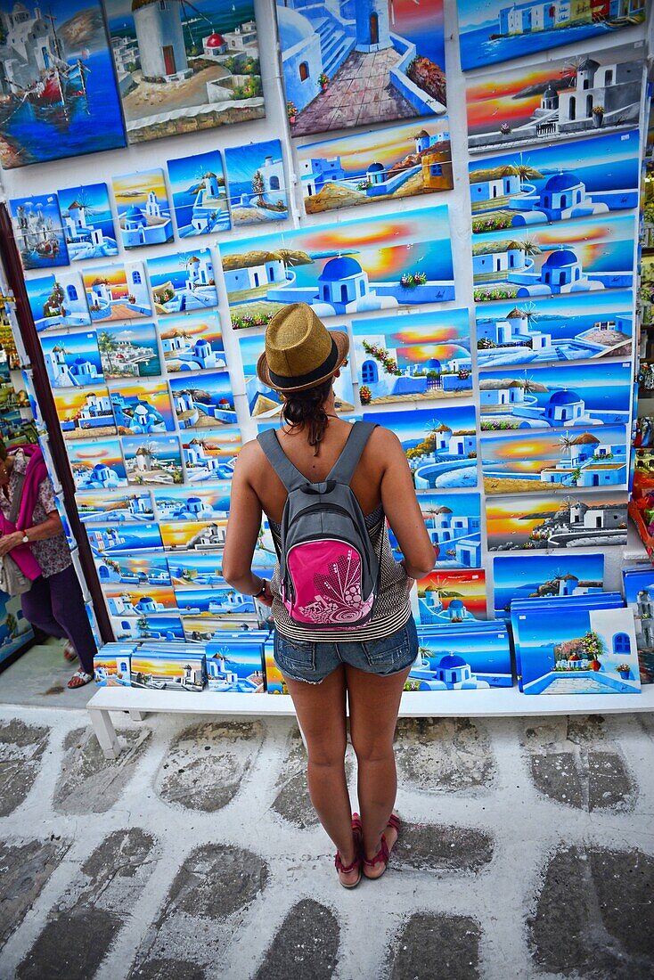 Junge Frau betrachtet Gemälde in einem Straßenladen, Mykonos, Griechenland