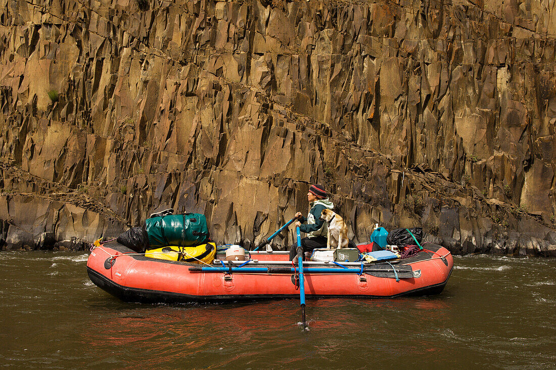 Junge Frau und Hund auf einem aufblasbaren Floß auf dem John Day River, Oregon.