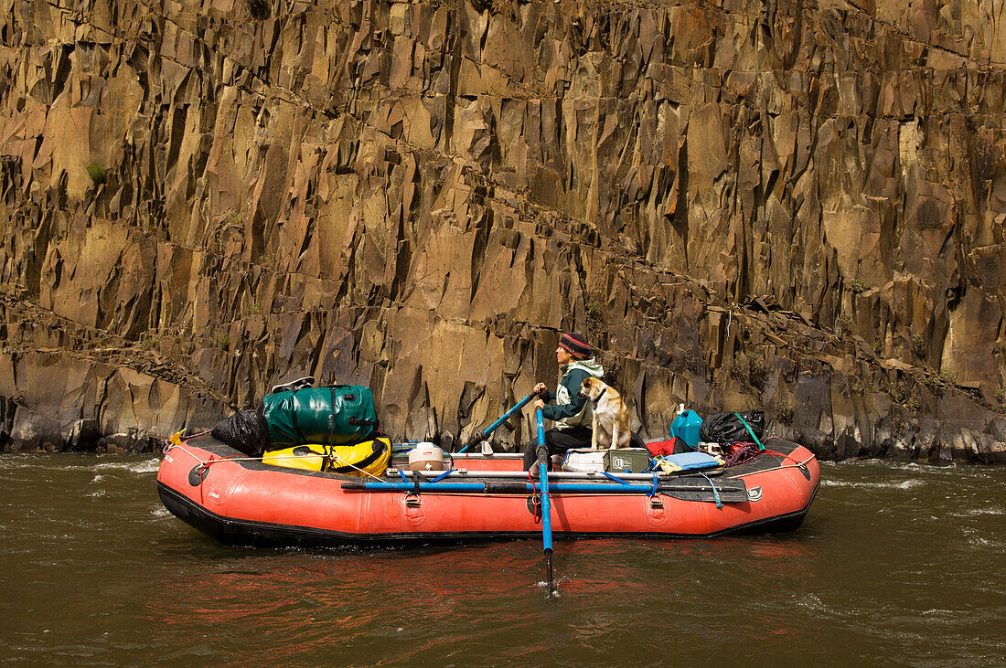 Young woman and dog on inflatable raft on the John Day River, Oregon.