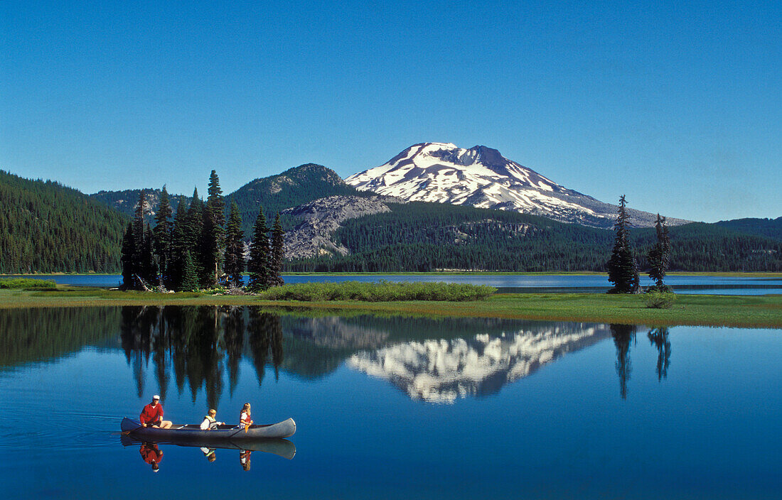 Father and children in canoe, Sparks Lake and South Sister, Cascade Mountains, Oregon.