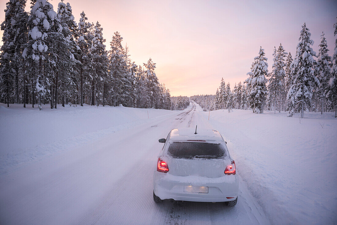 Autofahrt auf vereisten, schneebedeckten Straßen während einer Reise in Lappland innerhalb des Polarkreises in Finnland