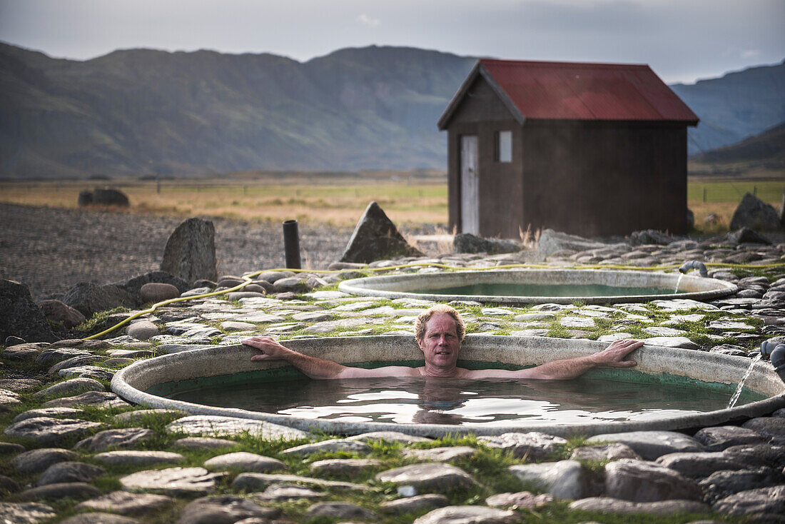 Tourist beim Baden in den Hoffell Hot Tubs bei Hofn, Südostisland