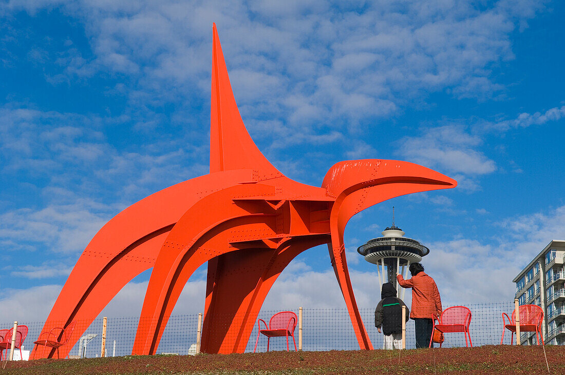 Mutter und Sohn betrachten Alexander Calders "Eagle" im Olympic Sculpture Park des Seattle Art Museums mit der Space Needle in der Ferne; Seattle, Washington.
