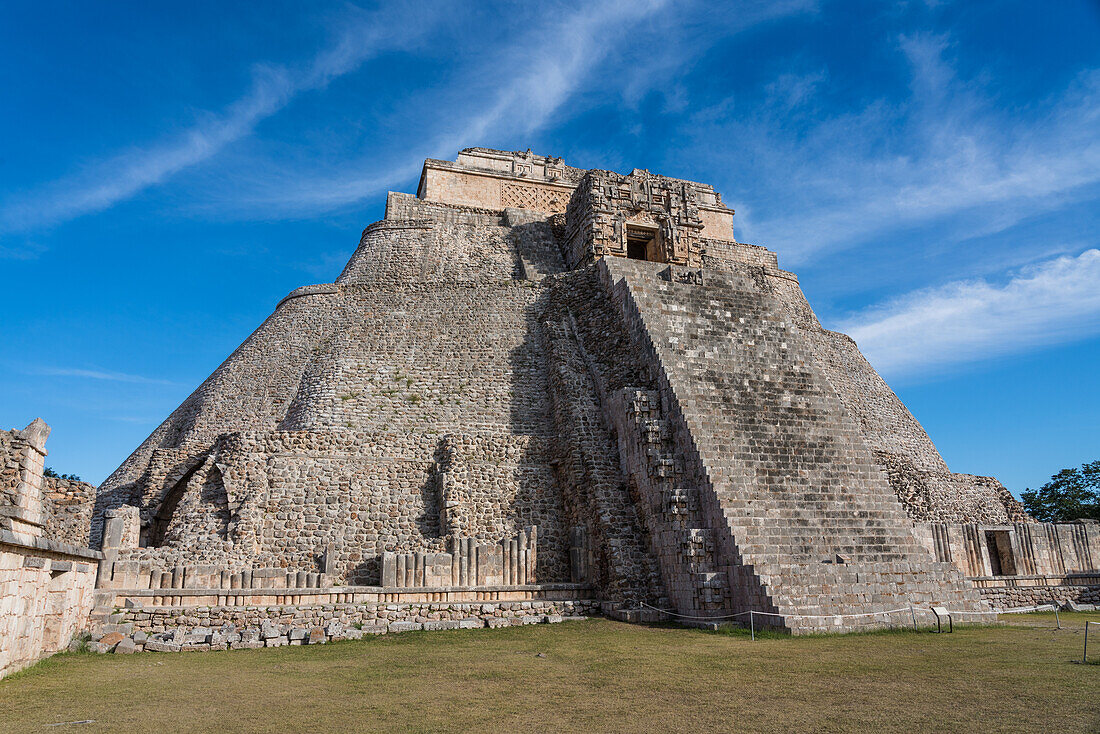 Die Westfassade der Pyramide des Magiers, die auch als Pyramide des Zwerges bekannt ist, blickt auf das Vogelviereck. Sie ist das höchste Bauwerk in den prähispanischen Maya-Ruinen von Uxmal, Mexiko, und ragt etwa 35 Meter in die Höhe. Der Tempel am oberen Ende der Treppe ist im Chenes-Stil erbaut, während der obere Tempel im Puuc-Stil gehalten ist.
