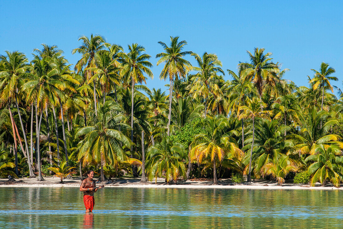Insel Taha'a, Französisch-Polynesien. Ein einheimischer Junge spielt auf der Ukulele, um ein Mädchen auf dem Motu Mahana zu umwerben, Taha'a, Gesellschaftsinseln, Französisch-Polynesien, Südpazifik.