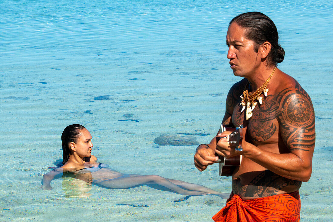 Insel Taha'a, Französisch-Polynesien. Ein einheimischer Junge spielt die Ukulele, um Ihr Mädchen auf dem Motu Mahana zu umwerben, Taha'a, Gesellschaftsinseln, Französisch-Polynesien, Südpazifik.