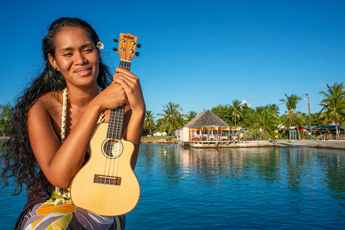 Beautiful local woman playing ukulele in Rangiroa beach, Tuamotu Islands, French Polynesia, South Pacific.