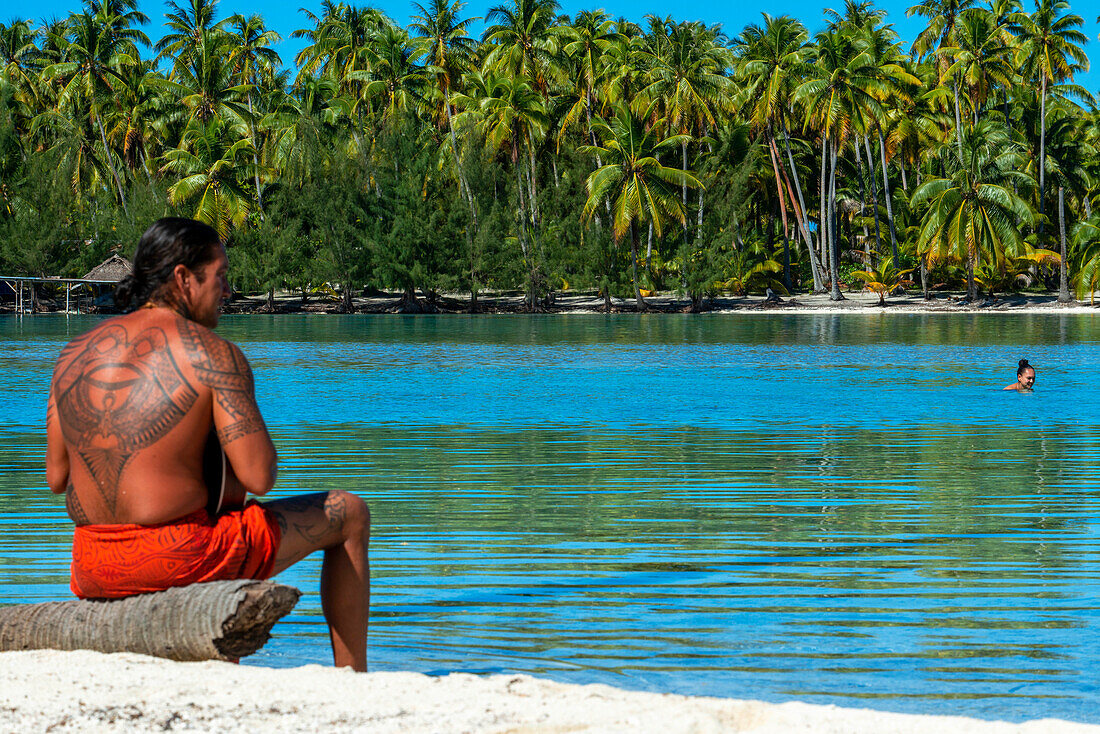 Insel Taha'a, Französisch-Polynesien. Ein einheimischer Junge spielt auf der Ukulele, um ein Mädchen auf dem Motu Mahana zu umwerben, Taha'a, Gesellschaftsinseln, Französisch-Polynesien, Südpazifik.