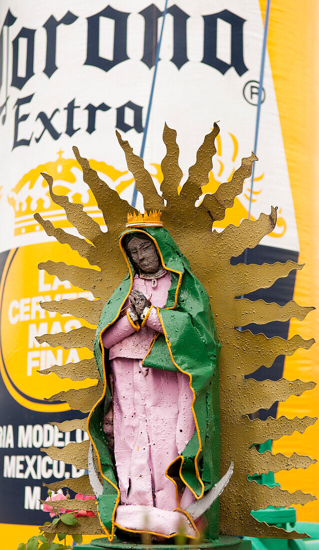Religious sculpture in front of inflatable beer bottle at the Corona brewery in Guadalajara, Mexico.