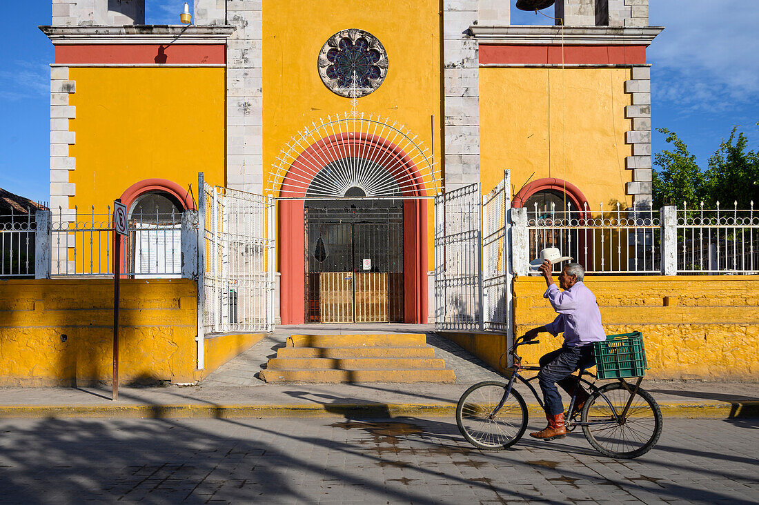 Mann beim Fahrradfahren vor der Kirche in San Blas, Riviera Nayarit, Mexiko.