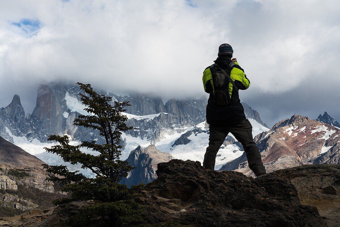 A hiker takes a photograph of Mount Fitz Roy shrouded in clouds in Los Glaciares National Park near El Chalten, Argentina. A UNESCO World Heritage Site in the Patagonia region of South America.