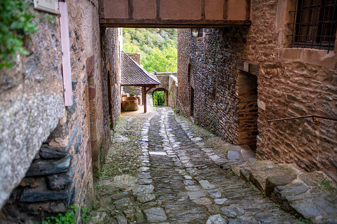 The small medieval village of Conques in France. It shows visitors its abbey-church and clustered houses topped by slate roofs. Crossing of narrow streets and monolith to the fallen ones in the war in the old medieval village of Conques on coats of the river Dordou