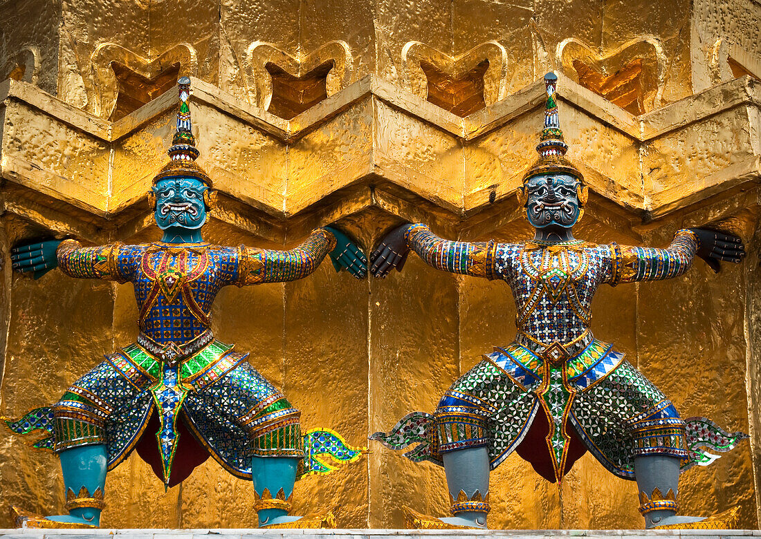 Mythische Wächterdämonen oder Yaksha, die den Sockel eines goldenen Chedi im Wat Phra Kaew auf dem Gelände des Grand Palace stützen; Bangkok, Thailand.
