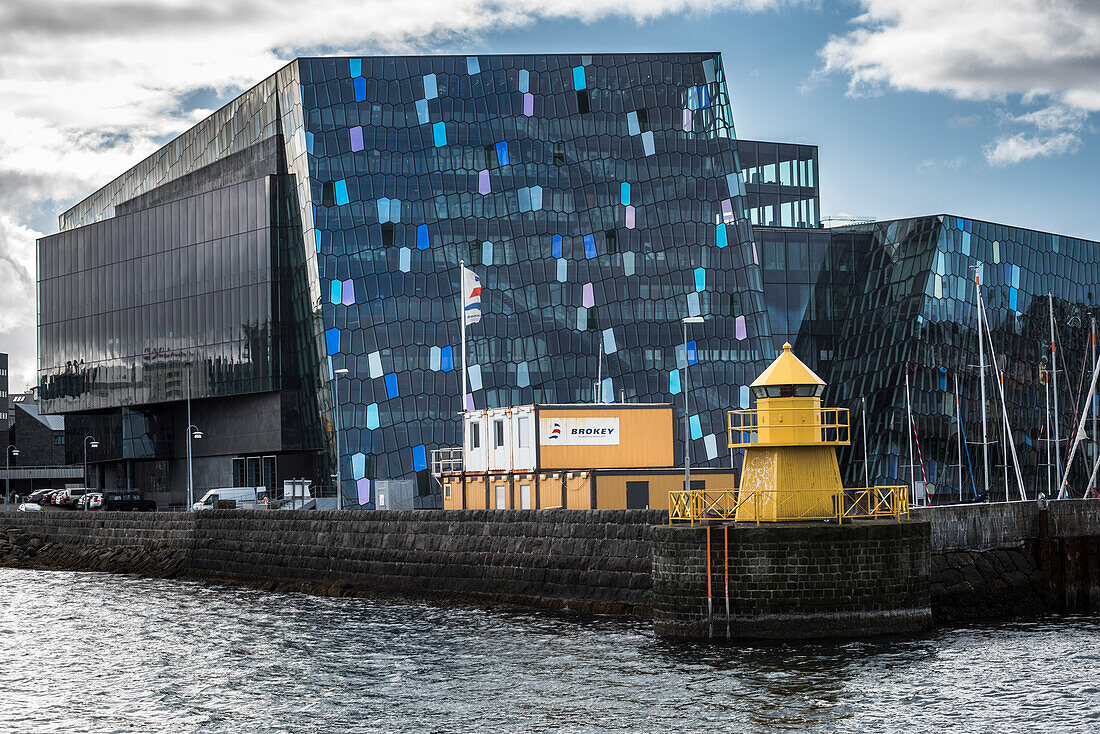 Konzertsaal und Konferenzzentrum Harpa mit gelbem Leuchtturm im Hafen von Reykjavik, Island