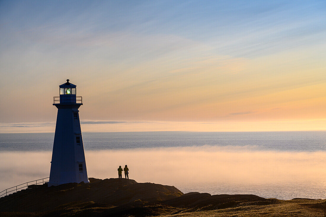 Besucher am Cape Spear Lighthouse mit einer Nebelbank über dem Atlantischen Ozean; St. John's, Neufundland, Kanada.