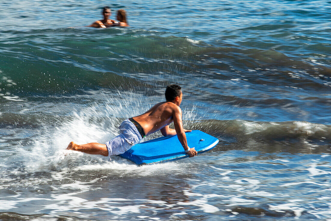 Surfer am Strand mit schwarzem Sand auf Pointe Venus, Tahiti, Französisch-Polynesien, Tahiti Nui, Gesellschaftsinseln, Französisch-Polynesien, Südpazifik.