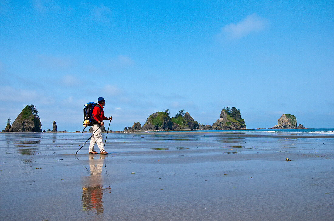Hiker with backpack on Shi Shi Beach at Point of Arches, Olympic National Park, Washington.