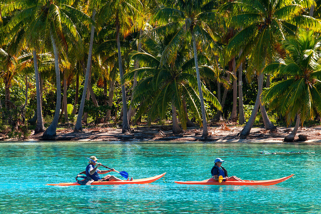 Kajakfahren am Strand der Insel Taha'a, Französisch-Polynesien. Motu Mahana Palmen am Strand, Taha'a, Gesellschaftsinseln, Französisch-Polynesien, Südpazifik.