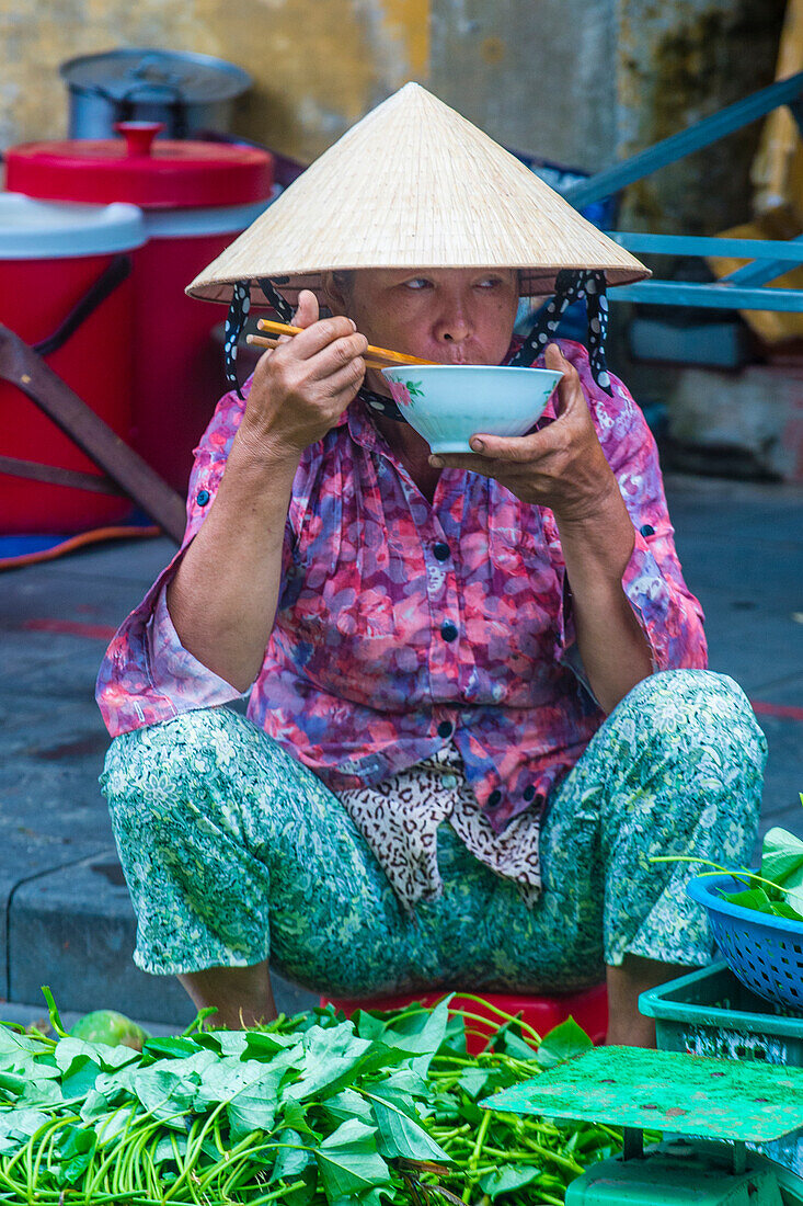 Vietnamesische Frau verkauft Gemüse auf einem Markt in Hoi An, Vietnam