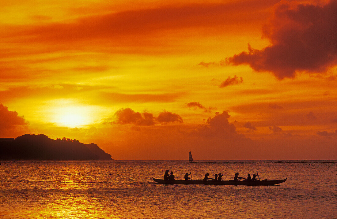 Guam, Micronesia: outrigger canoe paddlers at sunset at Tumon Bay resort area.