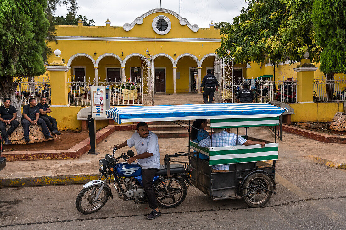 Ein Mototaxi mit Motorradanhänger vor dem Stadtpalast oder Rathaus der Stadt Muna, Yucatan, Mexiko.