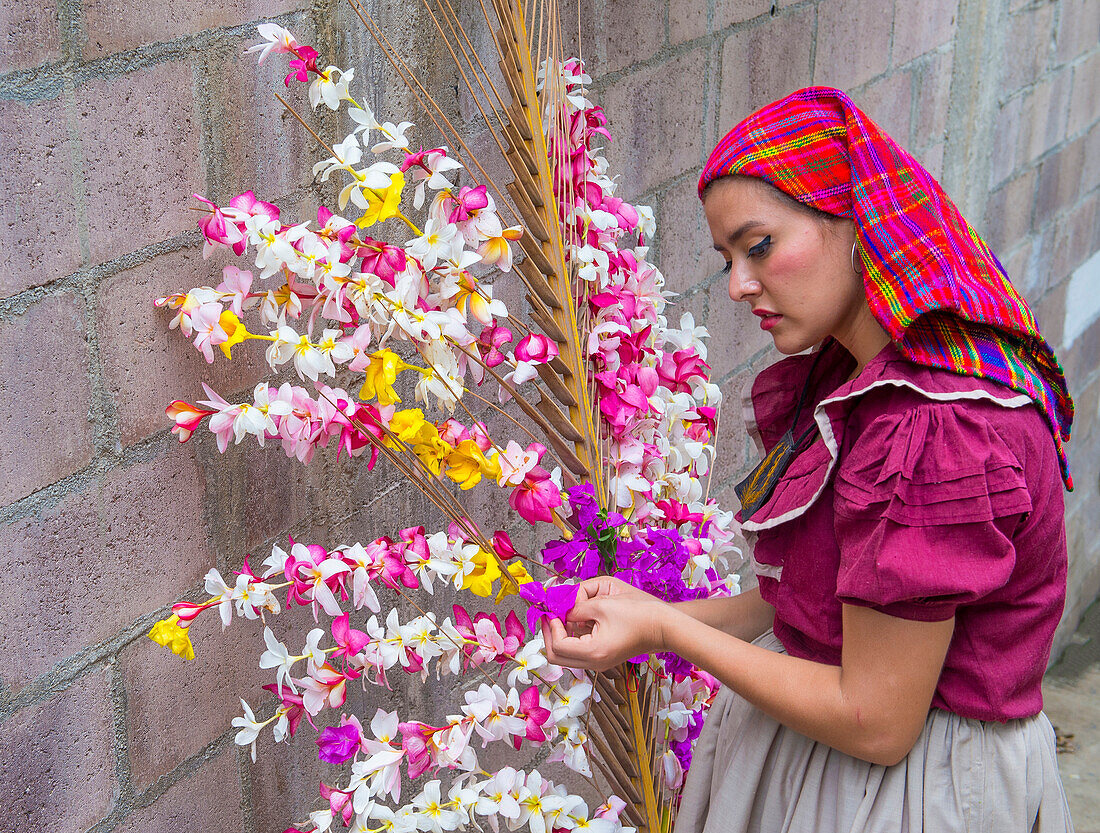 A Salvadoran woman decorates palm fronds with flowers during the Flower & Palm Festival in Panchimalco, El Salvador