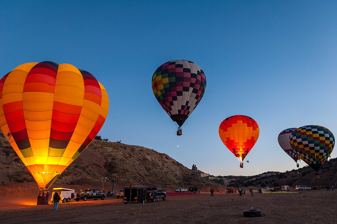 Heißluftballons beim Morgengrauen mit Church Rock im Hintergrund; Red Rock Balloon Rally im Red Rock State Park, Gallup, New Mexico.