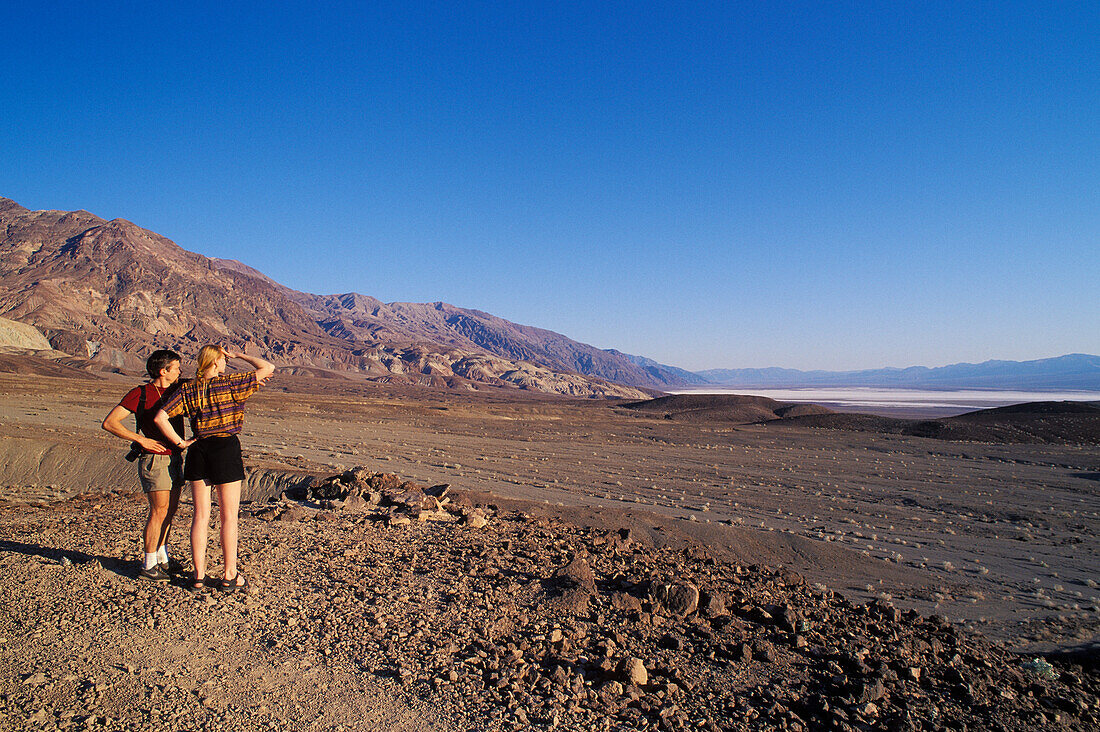 Ein Besucherpaar aus Europa betrachtet die Aussicht vom Artist's Drive auf das Badwater Basin im Death Valley National Park, Kalifornien.