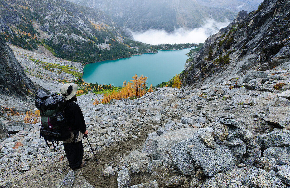 Rucksacktourist mit Blick auf den Colchuck Lake vom Aasgard Pass, The Enchantments, Alpine Lakes Wilderness, Washington.