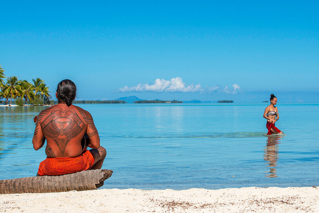 Insel Taha'a, Französisch-Polynesien. Ein einheimischer Junge spielt die Ukulele, um Ihr Mädchen auf dem Motu Mahana zu umwerben, Taha'a, Gesellschaftsinseln, Französisch-Polynesien, Südpazifik.