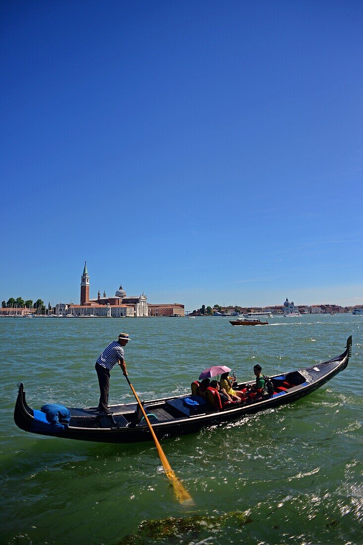 Touristen genießen eine Gondelfahrt mit Blick auf die Kirche San Giorgio Maggiore, Venedig, Italien