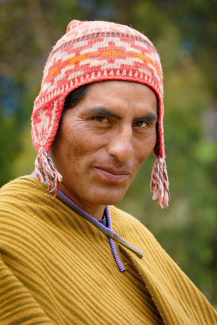 Quechua-Mann aus dem Dorf Misminay trägt einen traditionellen gewebten Poncho und eine gestrickte Ch'ullu-Mütze; Heiliges Tal, Peru.