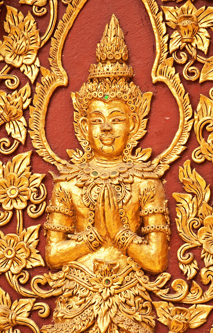 Detail einer goldenen Buddha-Figur an der Wand des buddhistischen Tempels Wat Mahawan in Chiang Mai, Thailand.