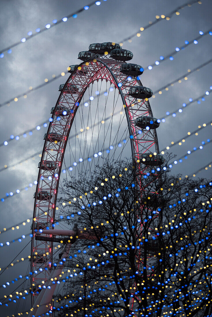 Das London Eye durch die nächtliche Weihnachtsbeleuchtung gesehen, South Bank, London, England