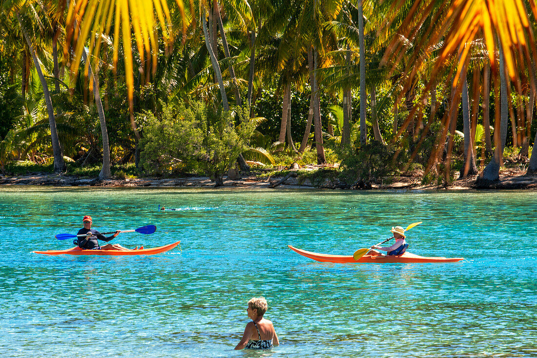 Kajakfahren am Strand der Insel Taha'a, Französisch-Polynesien. Motu Mahana Palmen am Strand, Taha'a, Gesellschaftsinseln, Französisch-Polynesien, Südpazifik.
