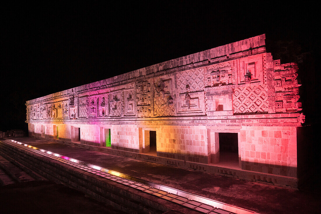 Das Westgebäude des Nonnenklosters wird in den prähispanischen Maya-Ruinen von Uxmal, Mexiko, von farbigen Lichtern beleuchtet.