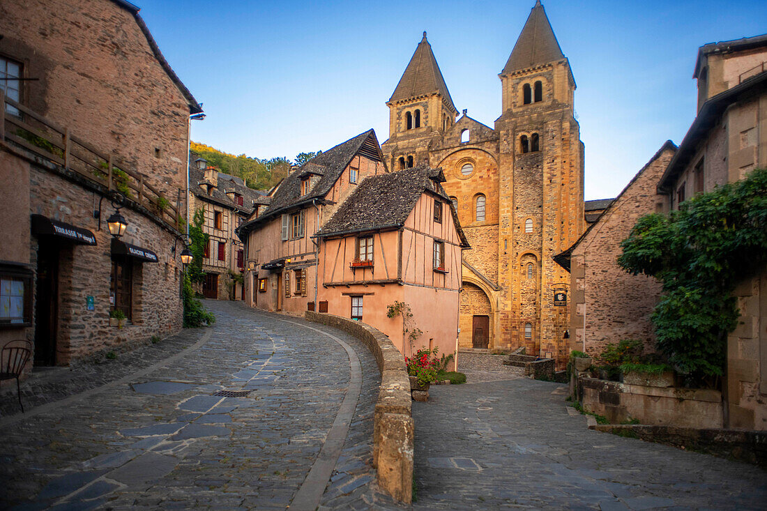 Das kleine mittelalterliche Dorf von Conques in Frankreich. Es zeigt dem Besucher seine Abteikirche und die mit Schieferdächern gedeckten Häusergruppen. Durchquerung der engen Gassen und Monolith zu den Gefallenen im Krieg im alten mittelalterlichen Dorf von Conques auf Mänteln des Flusses Dordou