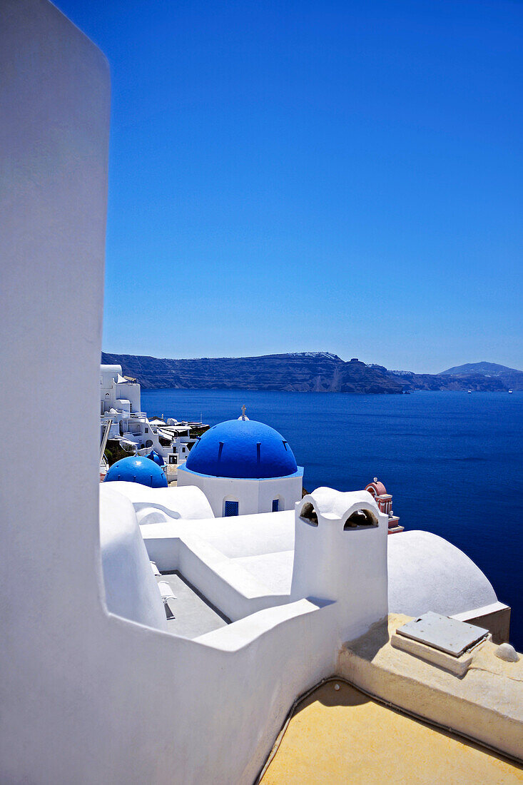 Hillside buildings with traditional church blue domes in Oia, Santorini, Greek Islands, Greece