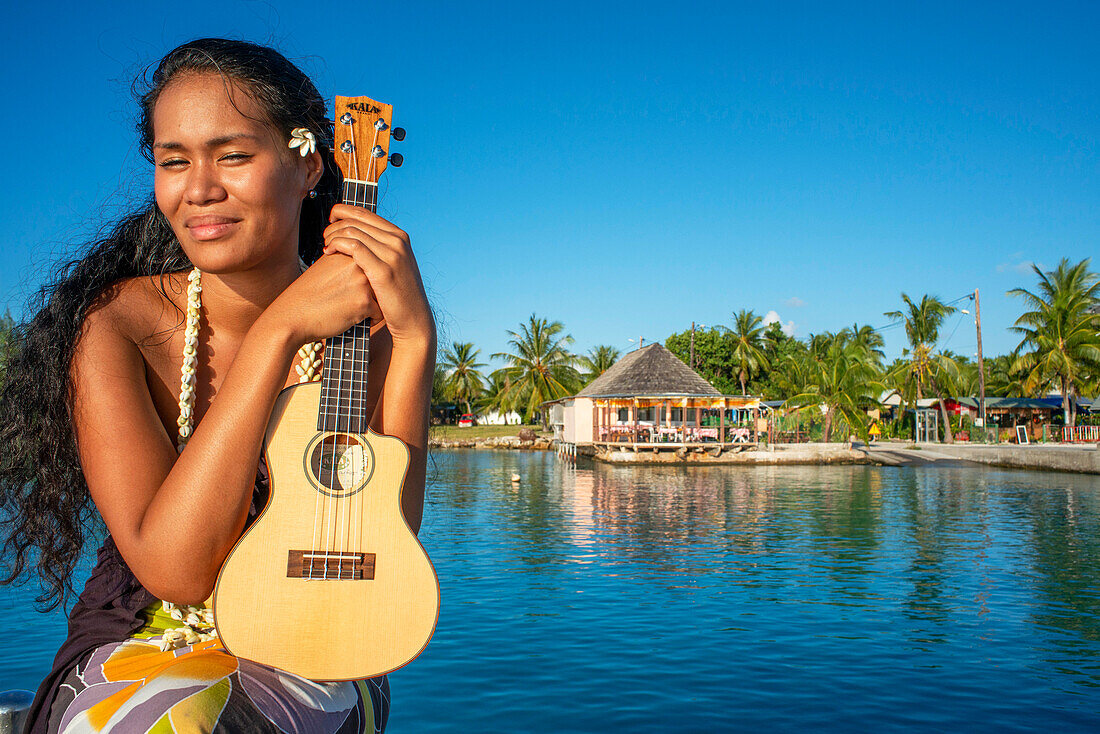 Schöne einheimische Frau spielt Ukulele am Strand von Rangiroa, Tuamotu-Inseln, Französisch-Polynesien, Südpazifik.