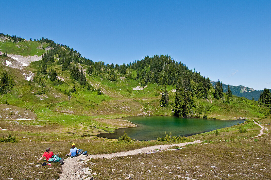 Zwei Wandererinnen beim Mittagessen am Heart Lake; High Divide Trail, Olympic National Park, Washington.