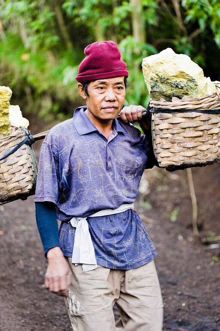 Black and White Portrait of a Sulphur Worker at Kawah Ijen, Java, Indonesia. Kawah Ijen is a volcano with an active crater and acid lake in East Java, Indonesia. It is an unbelievable and unmissable destination for anyone visiting Java or Bali. Not only is the view on the 4km walk up to the craters edge impressive, but what goes on there is mind boggling. Walking down to the bottom of Kwah Ijen (Ijen Crater), hundreds of Indonesian men, many in flipflops, are mining sulphur from the heart of the volcano. They load their baskets up with up to 80kg of sulphur, before starting the arduous and ext